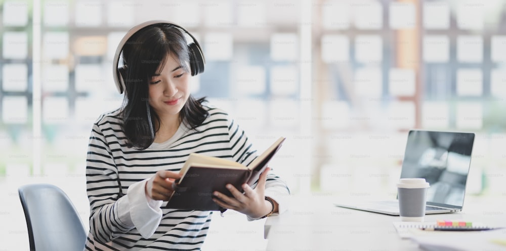 Junges Mädchen verbringt ihre Freizeit mit Lesen und Hören ihrer Lieblingsmusik mit On-Ear-Kopfhörern