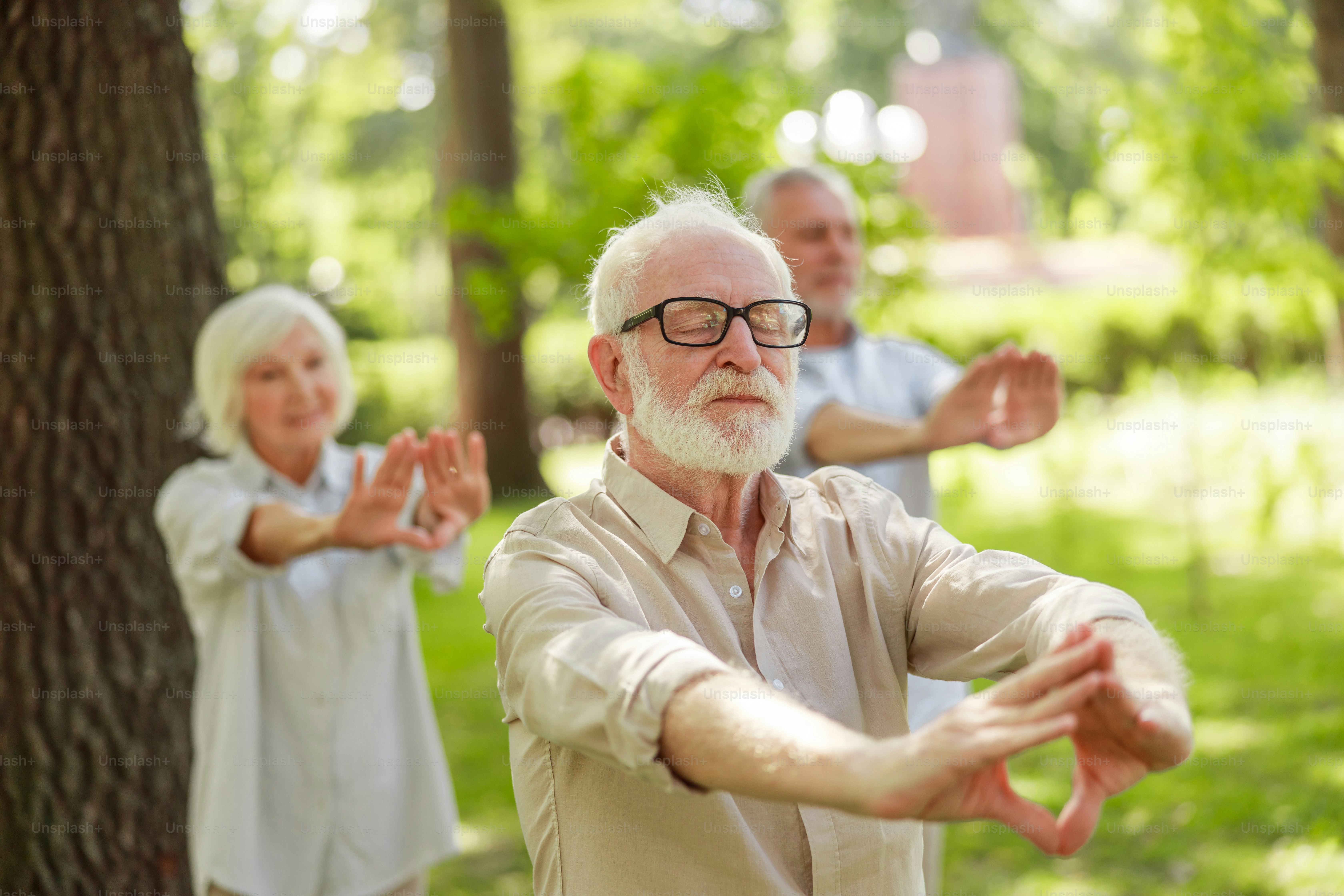 Vecchio signore che frequenta la lezione di qigong nel parco - Foto stock