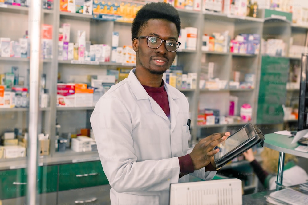 Confident African American man pharmacist standing in interior of pharmacy