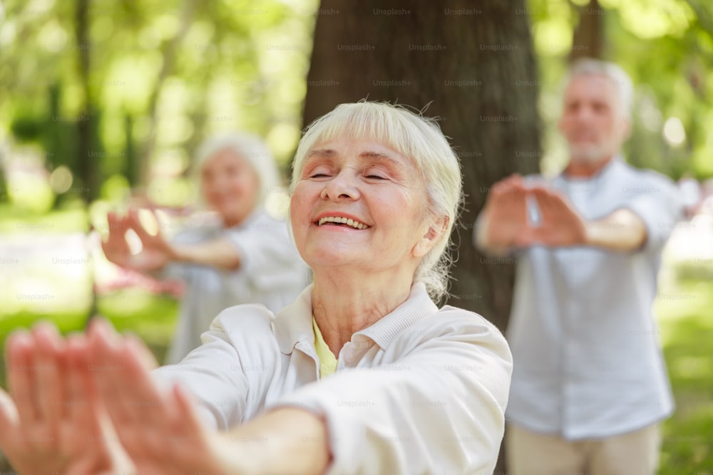 Smiling old woman doing qigong meditation exercise stock photo