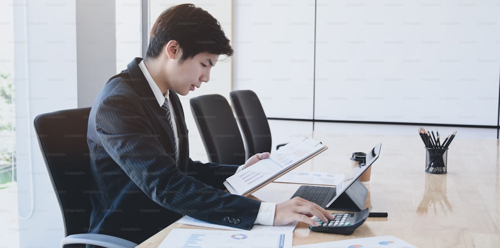 Male accountant analysing and reviewing expenditures for his company in the office room