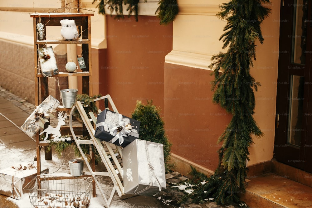 Regali di Natale alla moda e slitta di legno rustica con regali davanti al negozio al mercatino di Natale in strada della città. Decorazioni stradali natalizie. Spazio per il testo. Decorazione rustica