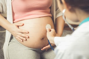 Glückliche schwangere Frau besuchen Gynäkologen Arzt im Krankenhaus oder medizinische Klinik für Schwangerschaftsberater. Arzt untersucht schwangeren Bauch für Baby und Mutter Gesundheitscheck-up. Gynäkologie-Konzept.