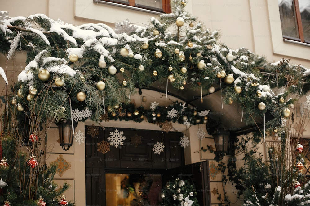 Christmas street decor. Stylish christmas fir branches with golden lights and festive ornaments on balcony at holiday market in city street. Space for text. Modern decoration