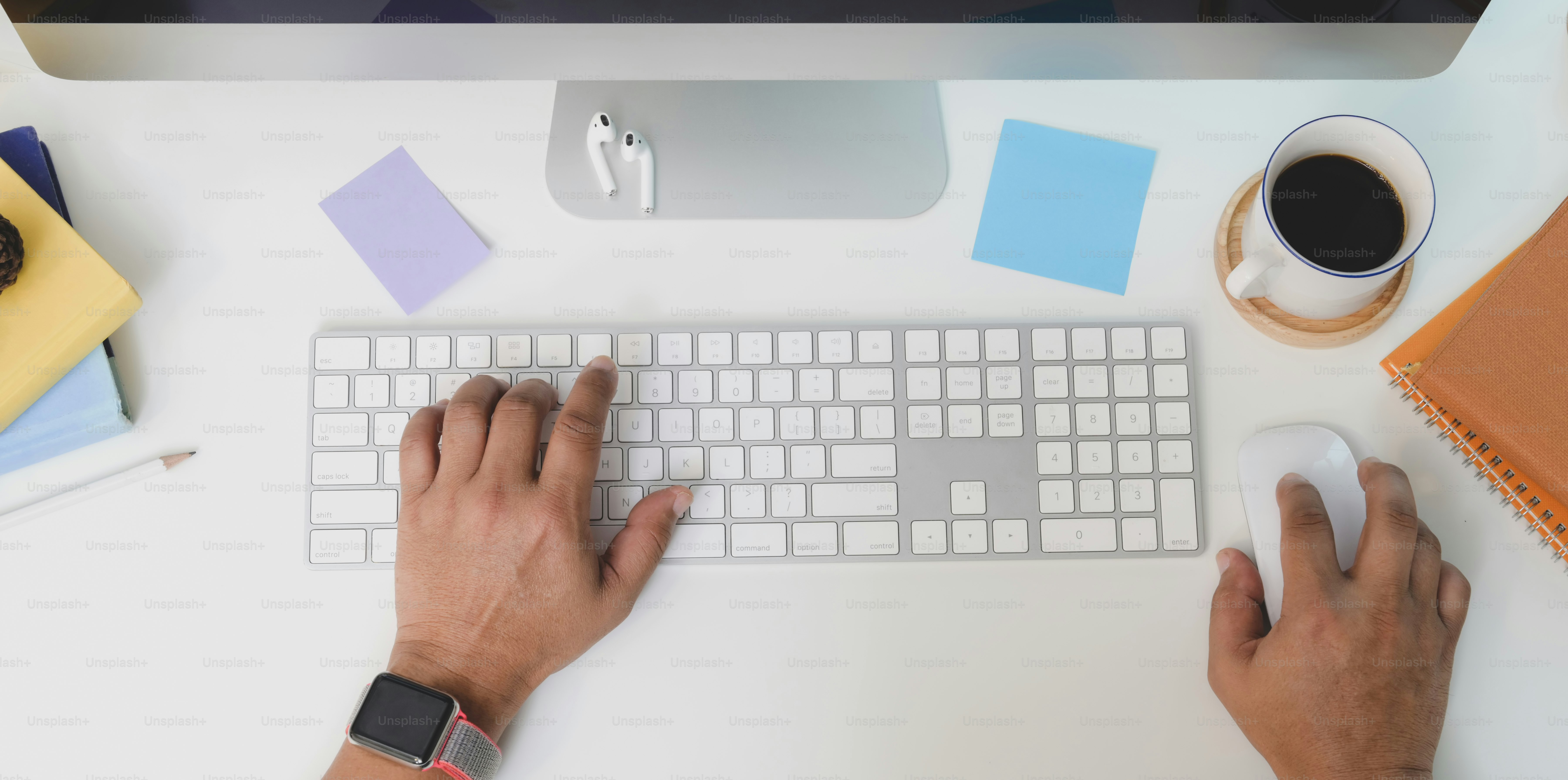 Top view of young man typing on keyboard computer while working on his project with coffee cup