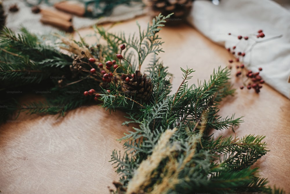 モミの枝、松ぼっくり、糸、果実、木製のテーブルの上のシナモン。素朴なクリスマスリースワークショップ。本物のスタイリッシュな静物画。クリスマスリース作り。