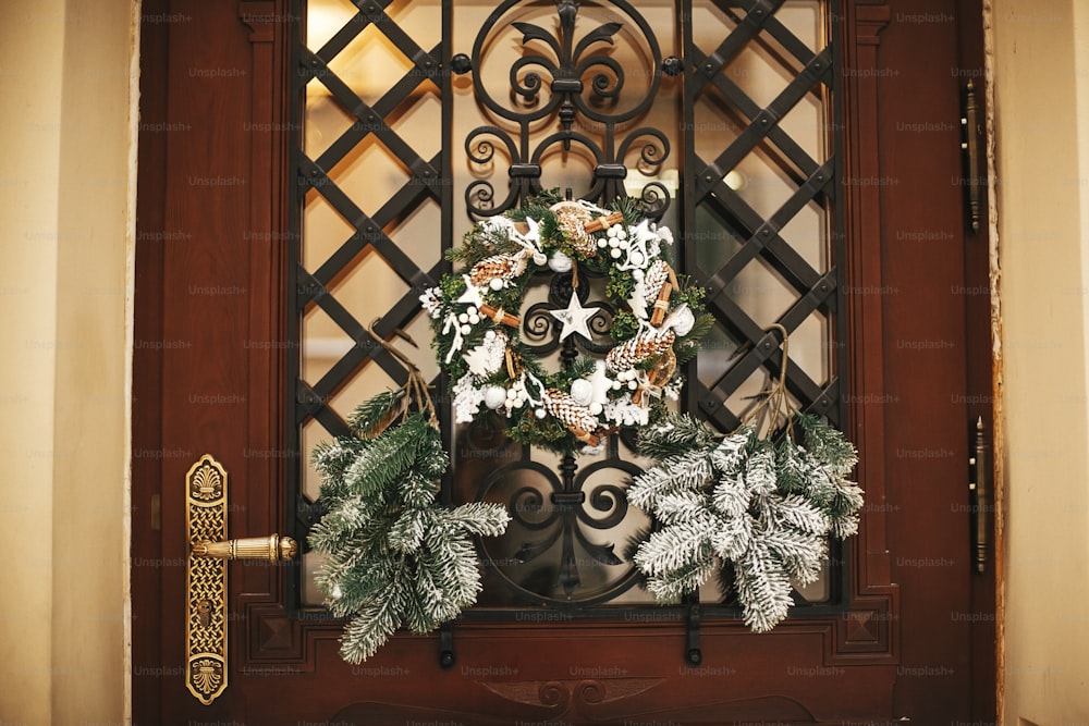 Christmas street decor. Stylish christmas rustic wreath with pine cones and white star at front door of store at holiday market in city street. Space for text. Rustic decoration
