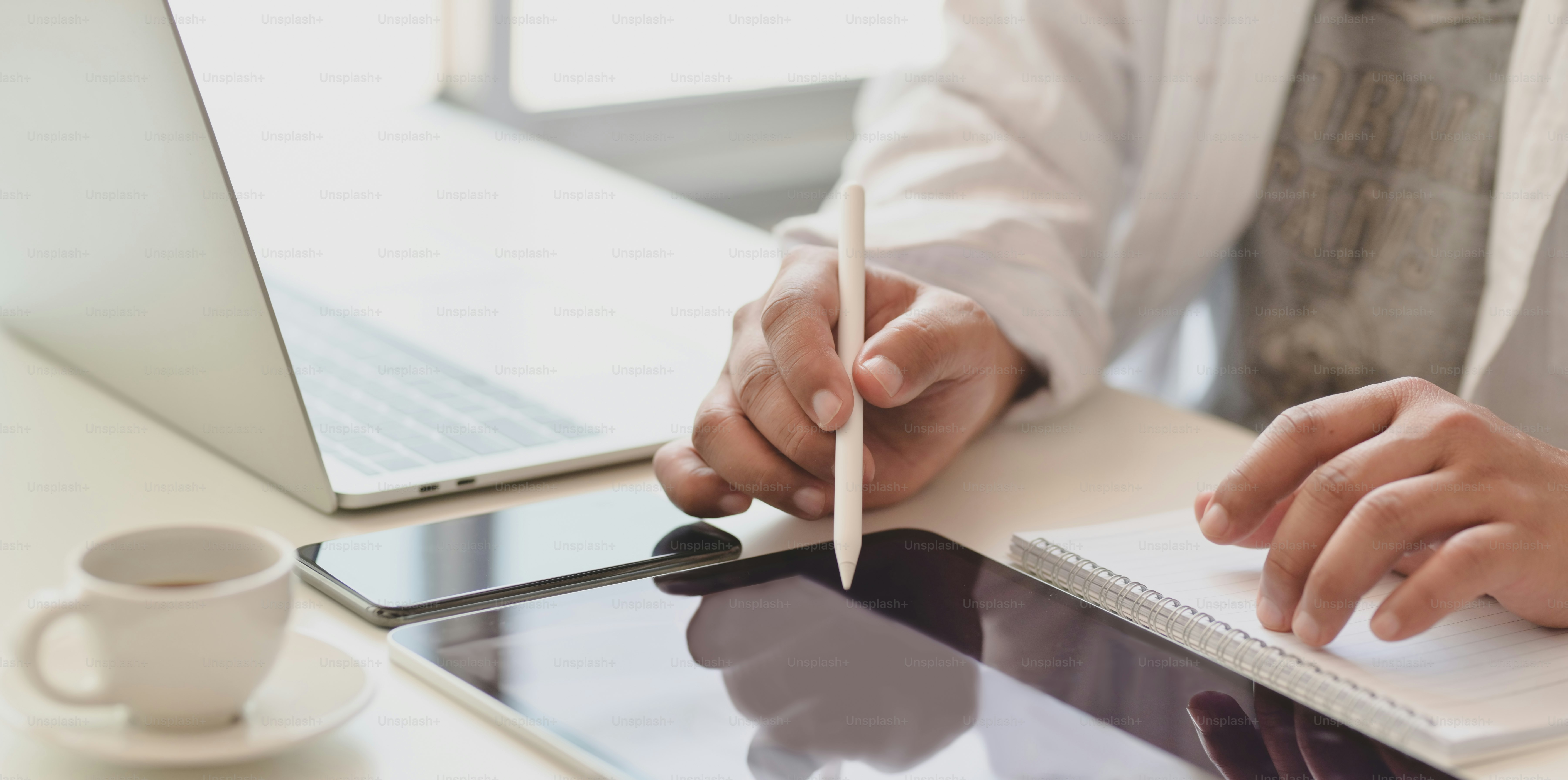 Cropped shot of young male freelancer writing on tablet while working on his project in his modern office room