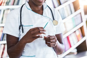 Medication nurse wearing white scrubs get a needle or shot ready for an injection. Black Female doctor with vial and syringe in hospital. Vaccination day