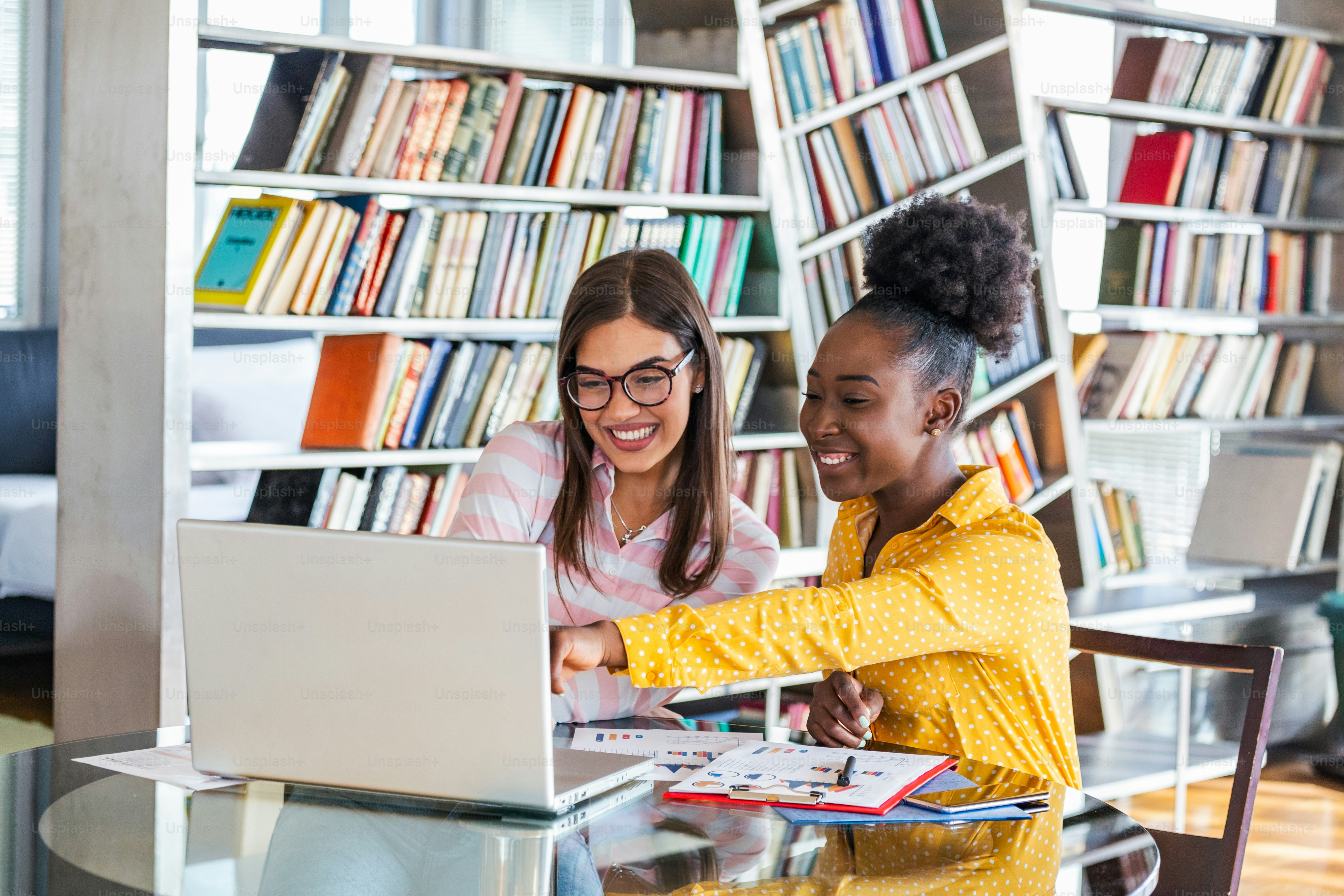 Women working on laptop in library - Photo on Unsplash+
