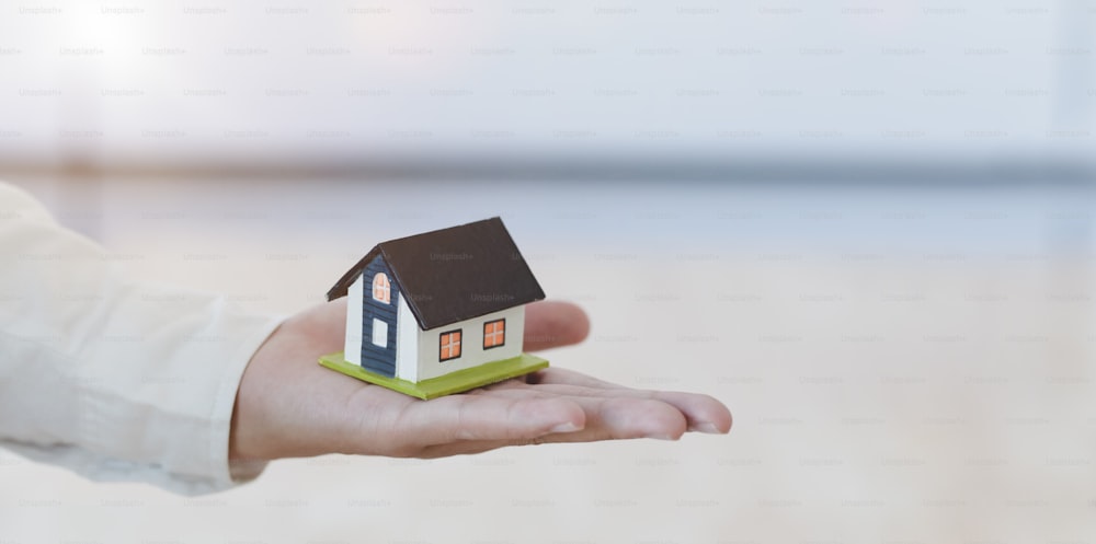 Property insurance concept : insurance agent holding a house model in his hand, symbol of home insurance