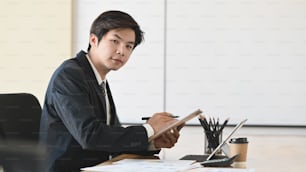 Young businessman sitting on business office and looking at camera.