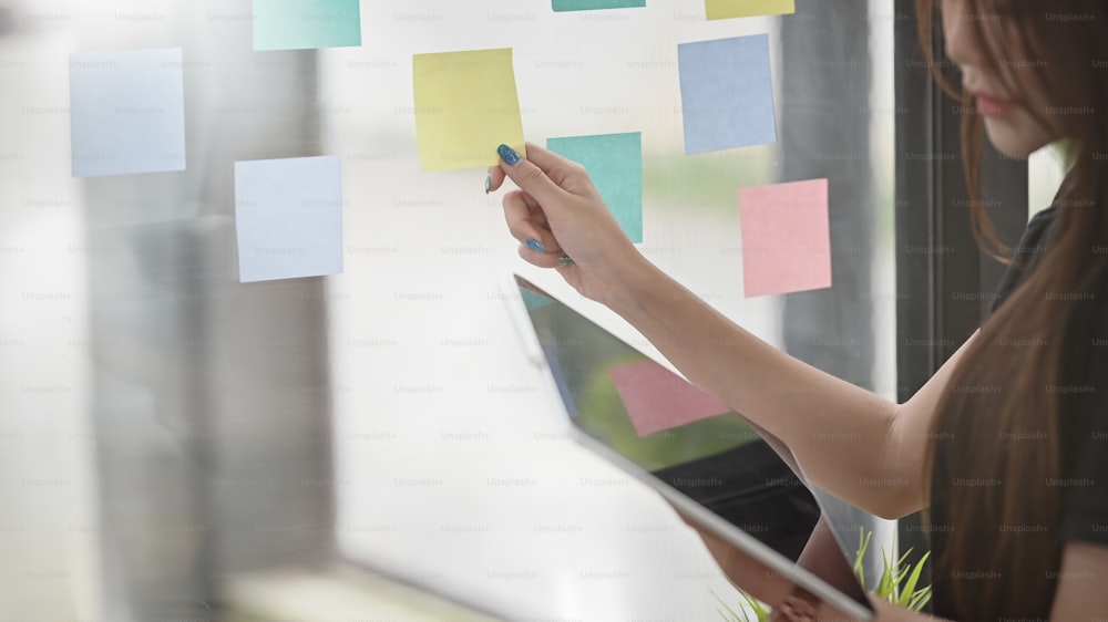 Side view female's hands her touch sticky notepaper and holding table.