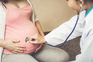 Happy pregnant woman visit gynecologist doctor at hospital or medical clinic for pregnancy consultant. Doctor examine pregnant belly for baby and mother healthcare check up. Gynecology concept.