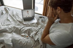 Sick young male complaining during video call with his consulting physician