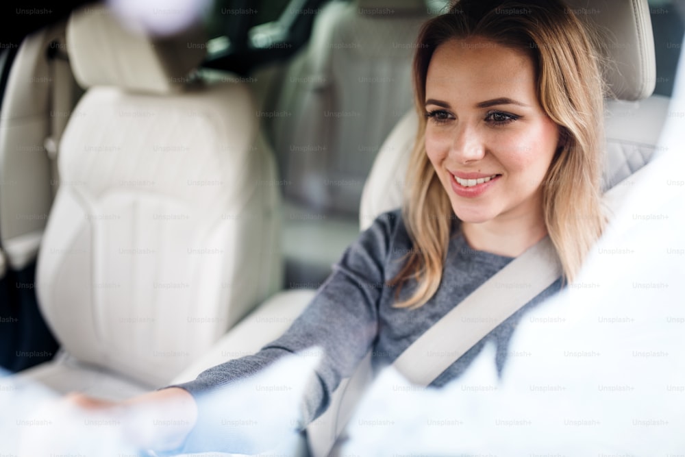 Motorista jovem feliz da mulher sentada no carro, dirigindo.