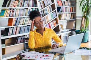 Young frustrated woman working at office desk in front of laptop suffering from chronic daily headaches, treatment online, appointing to a medical consultation, electromagnetic radiation, sick pay