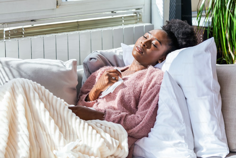Enfermedad, concepto de problema de virus estacional. Mujer enferma que tiene gripe acostada en el sofá mirando la temperatura en el termómetro. Mujer enferma acostada en cama con fiebre alta. Resfriado, gripe y migraña.