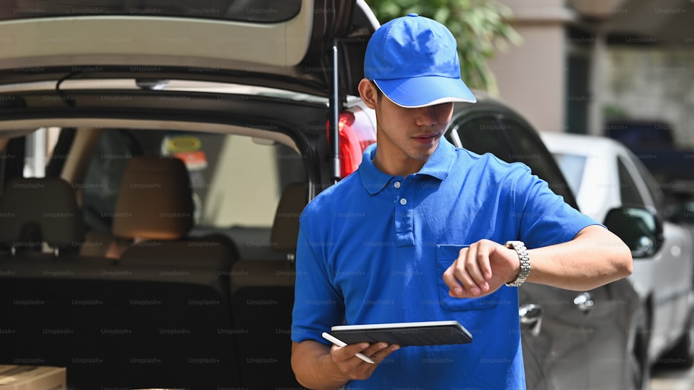 Deliveryman checking time and holding tablet.
