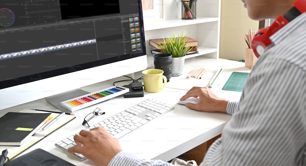 Montage vidéo avec un monteur professionnel sur ordinateur ajoutant des séquences d’étalonnage des couleurs.