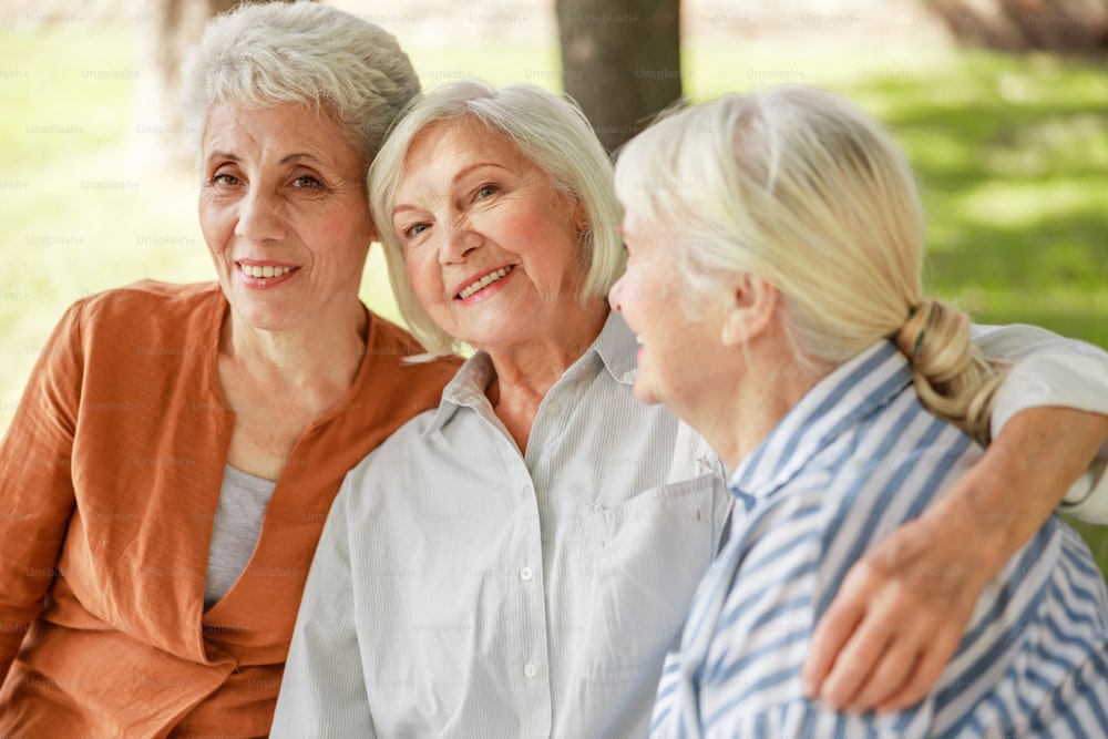 Drei alte Damen umarmen und lächeln Stockfoto
