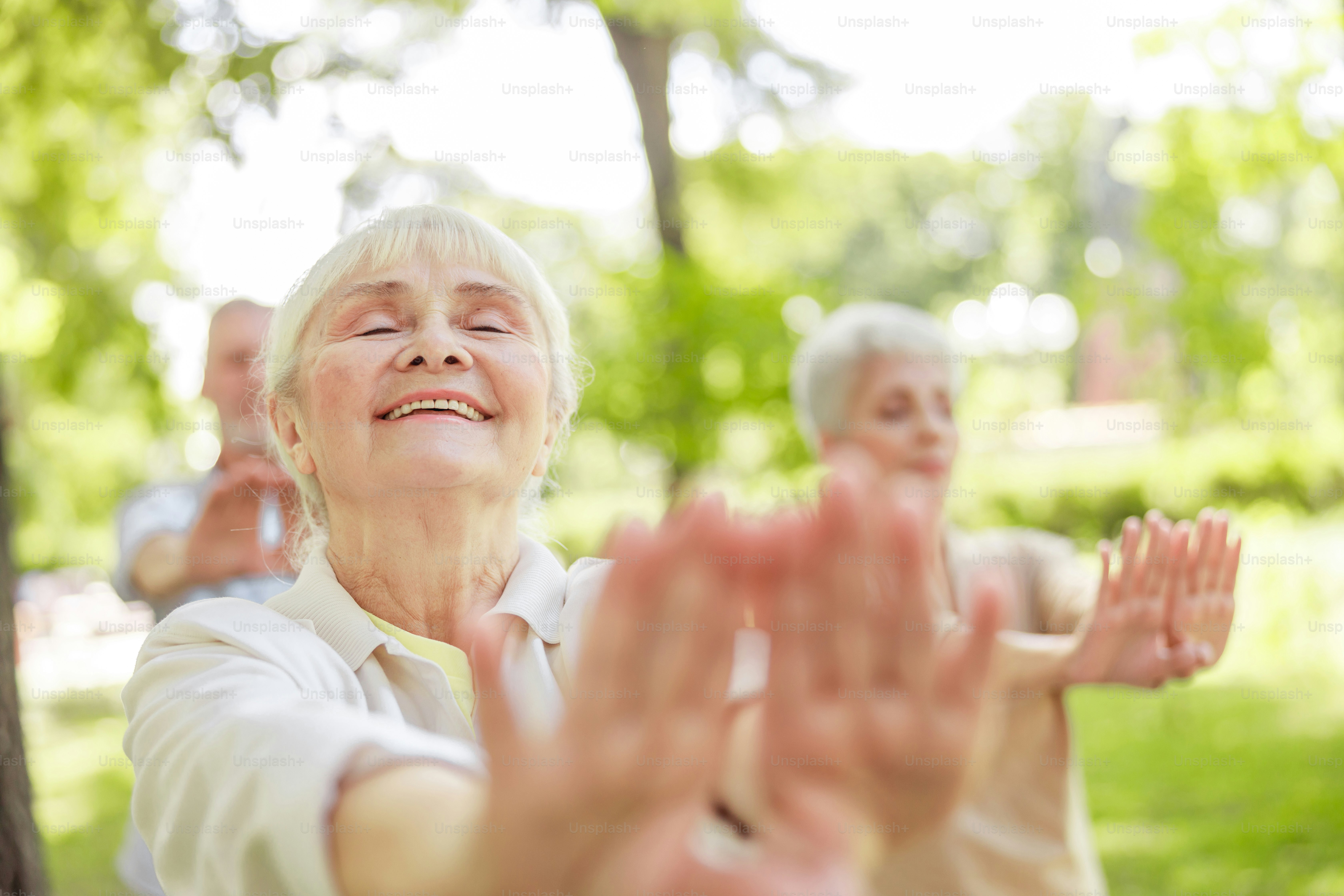 Signora anziana sorridente che fa esercizio di meditazione qigong fotografia stock. Banner del sito web