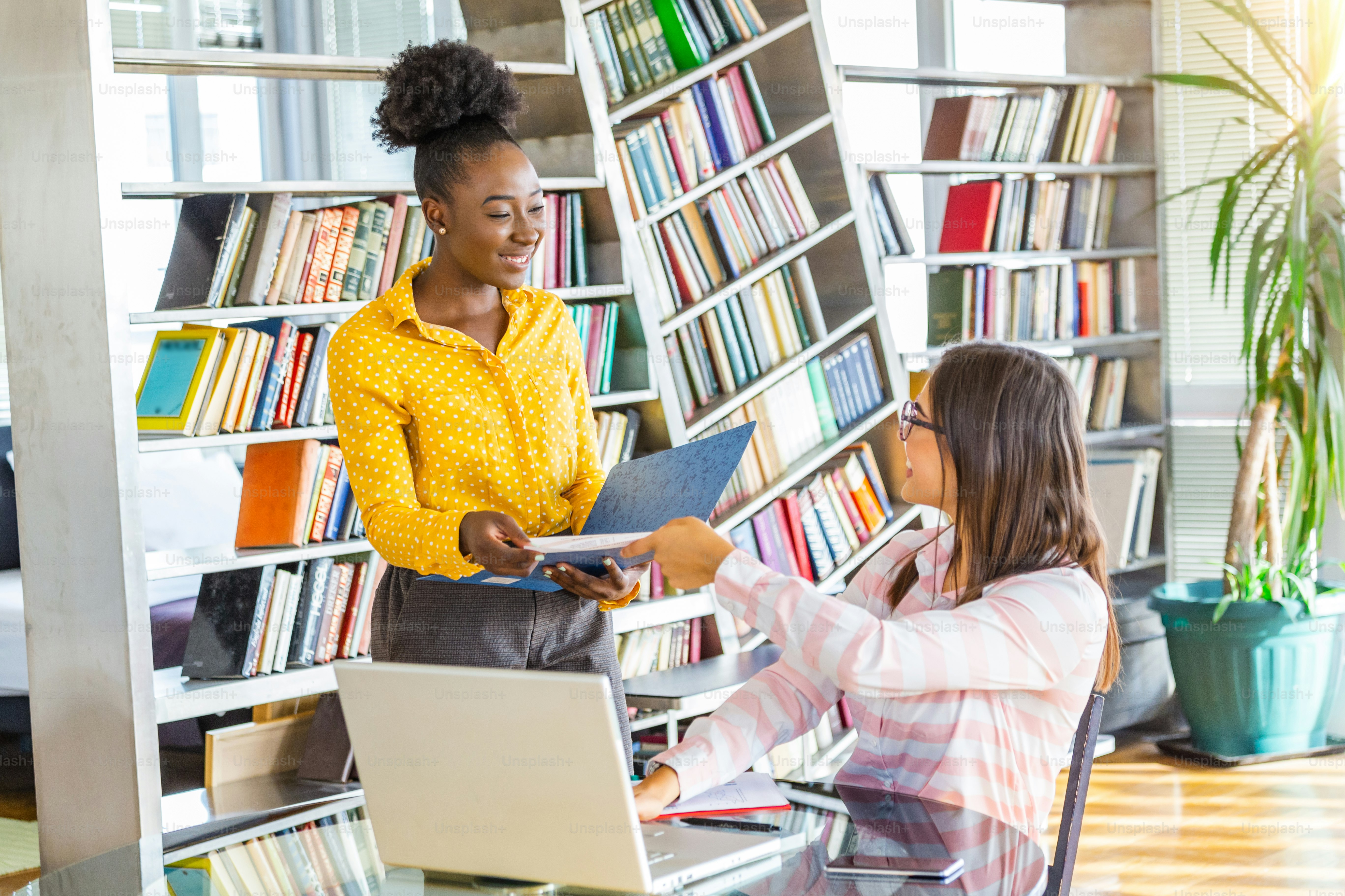 African American business woman holding papers and smiling.Young team of coworkers making great business discussion in modern coworking office.Teamwork people concept.