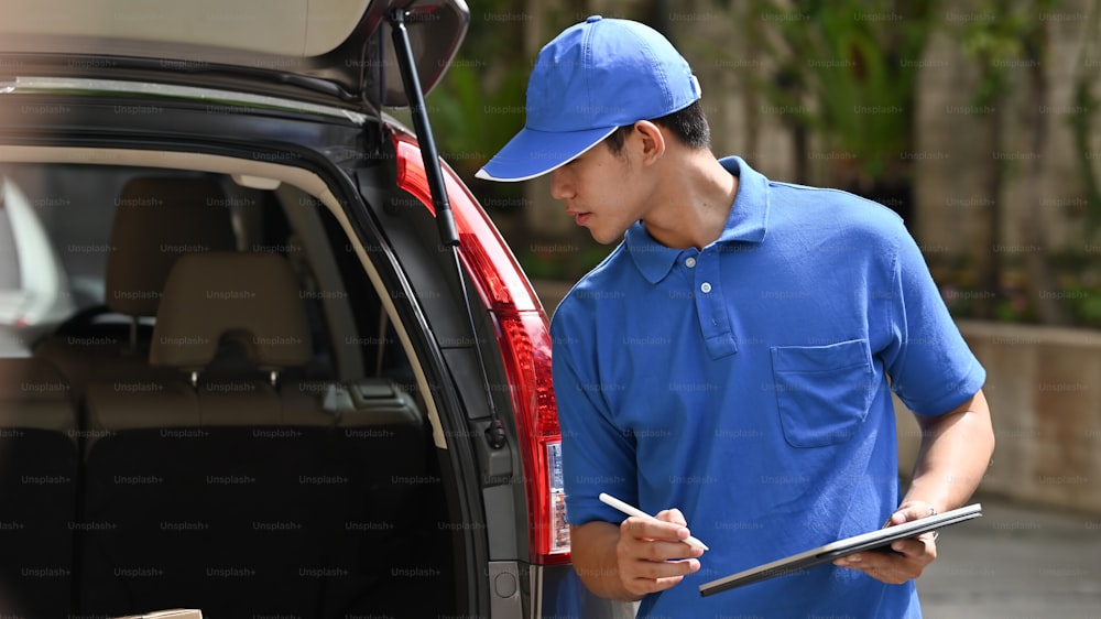 Young asian man working with post man, Delivery man checking with boxes in car.