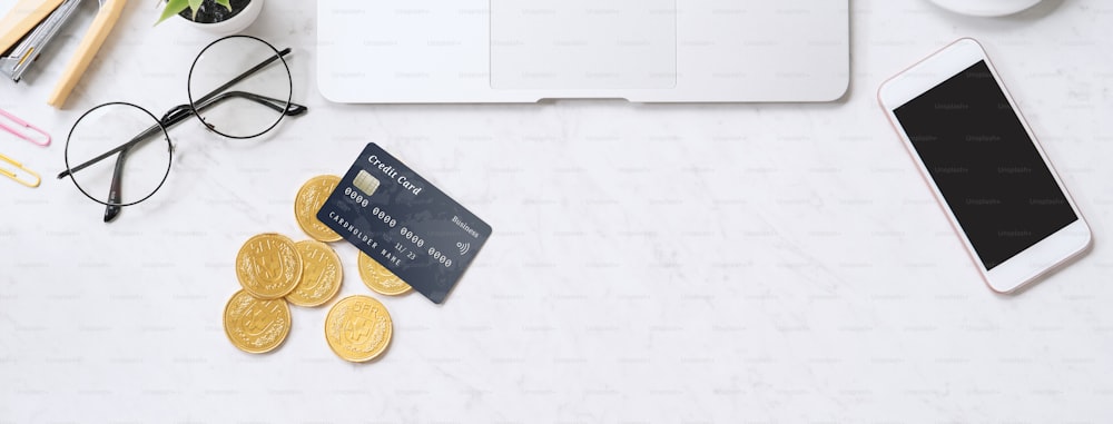 Concept of online payment with credit card with smart phone, laptop computer on office desk on clean bright marble table background, top view, flat lay