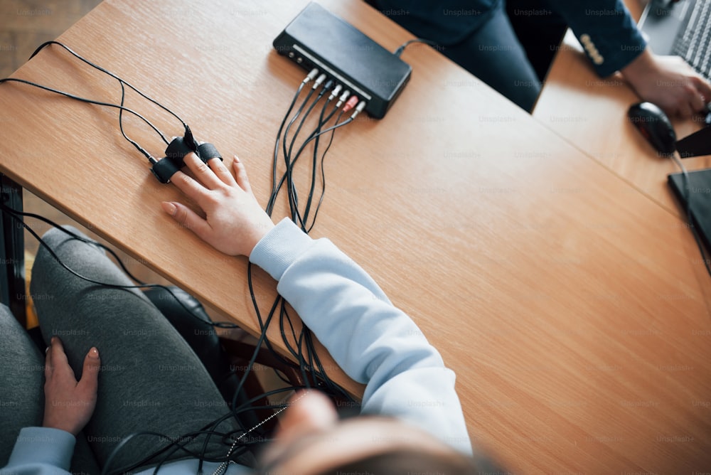 Top view. Girl passes lie detector in the office. Asking questions. Polygraph test.