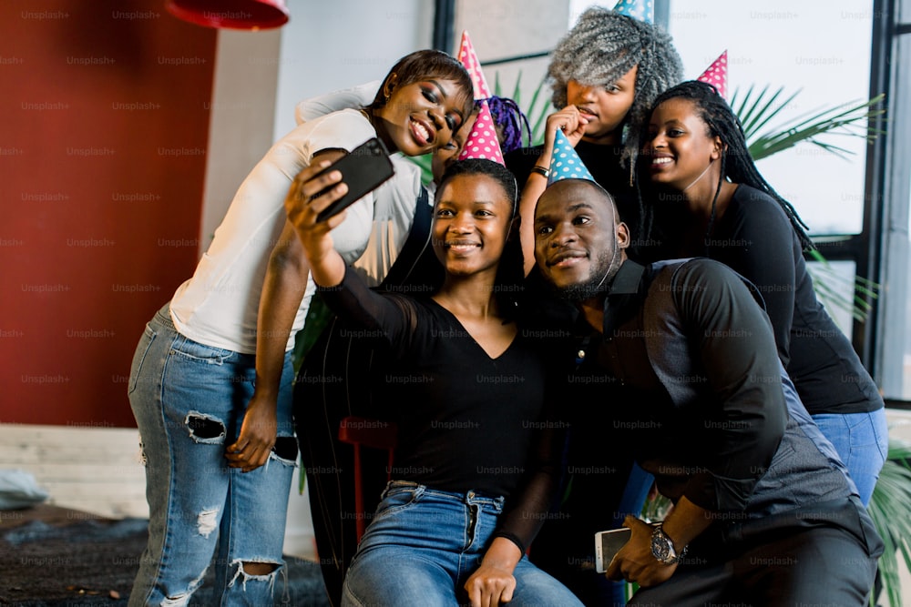 Young beautiful African American girls celebrate birthday and make a selfii on their smartphone.