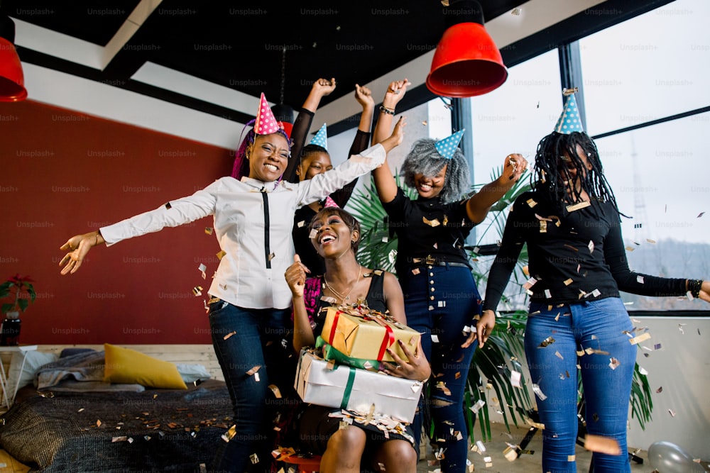 Glückliche afroamerikanische Freunde Mädchen unter fallendem Konfetti auf der Geburtstagsfeier
