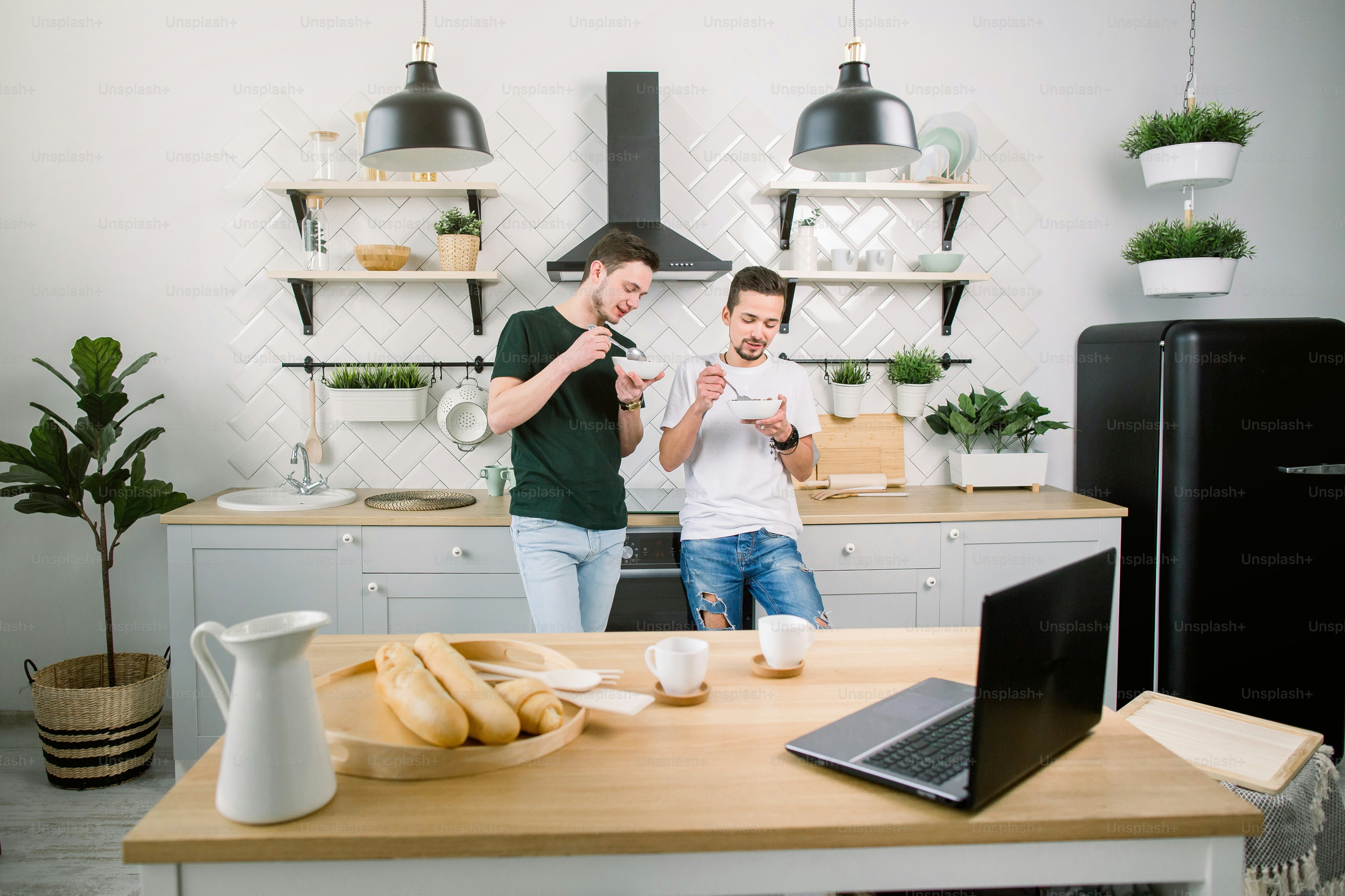 Happy homosexual boys talking each other and having breakfast. Everyday morning routine of gay couple life in kitchen at home