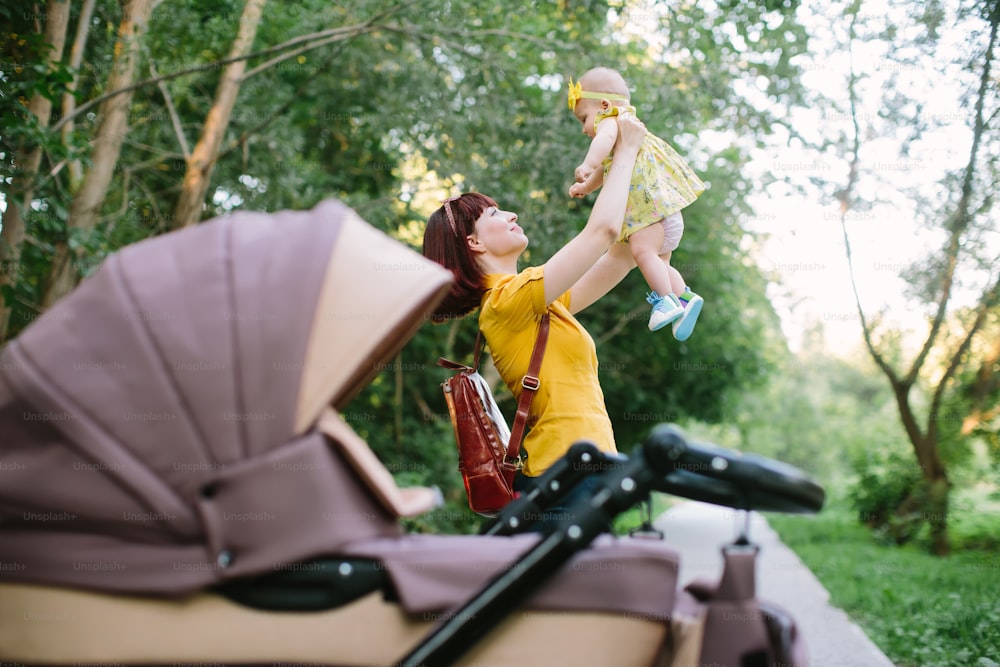 young mother with infant baby and carriage outdoors