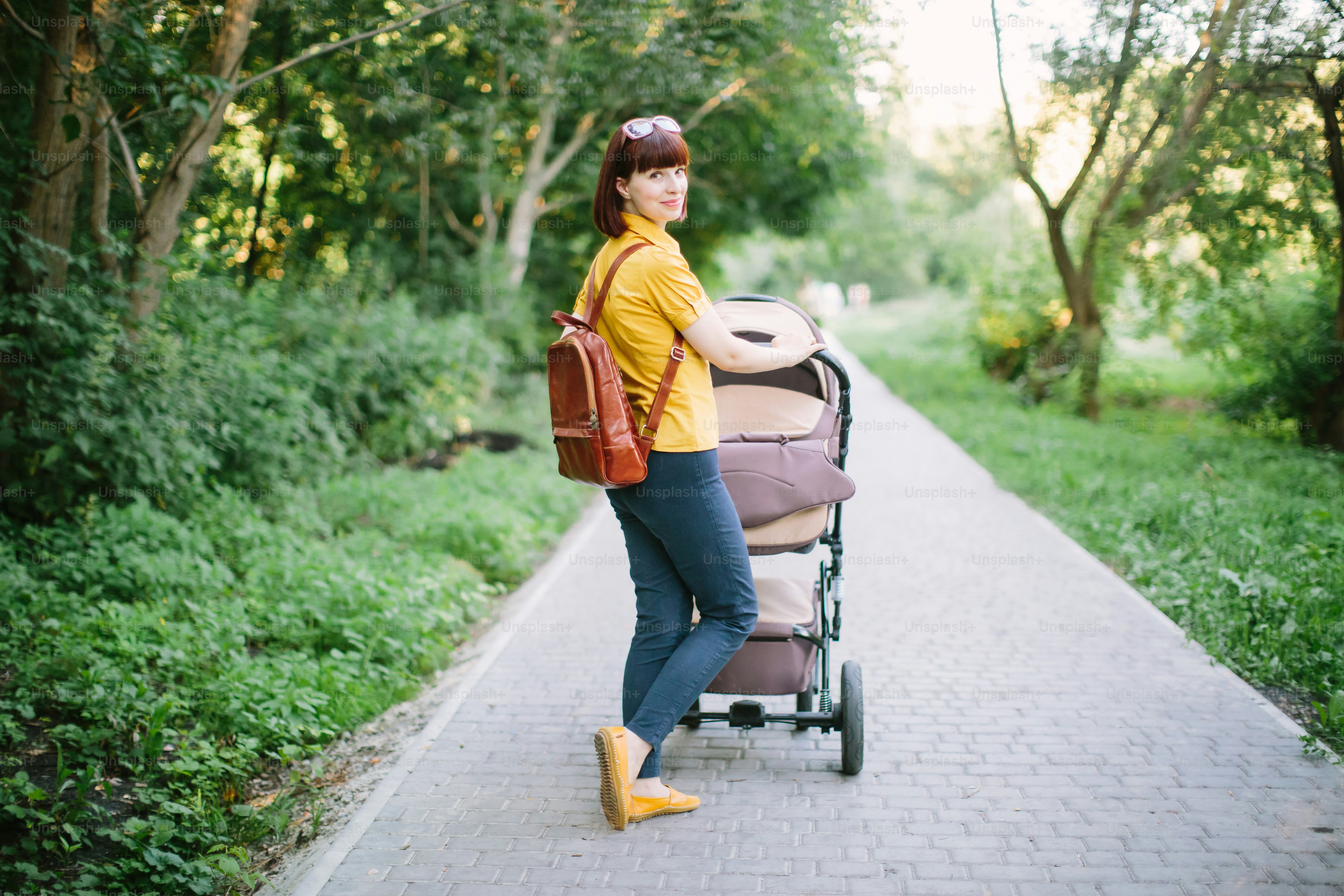 Ganzkörperporträt einer Mutter mit Kinderwagen. Junge Mutter