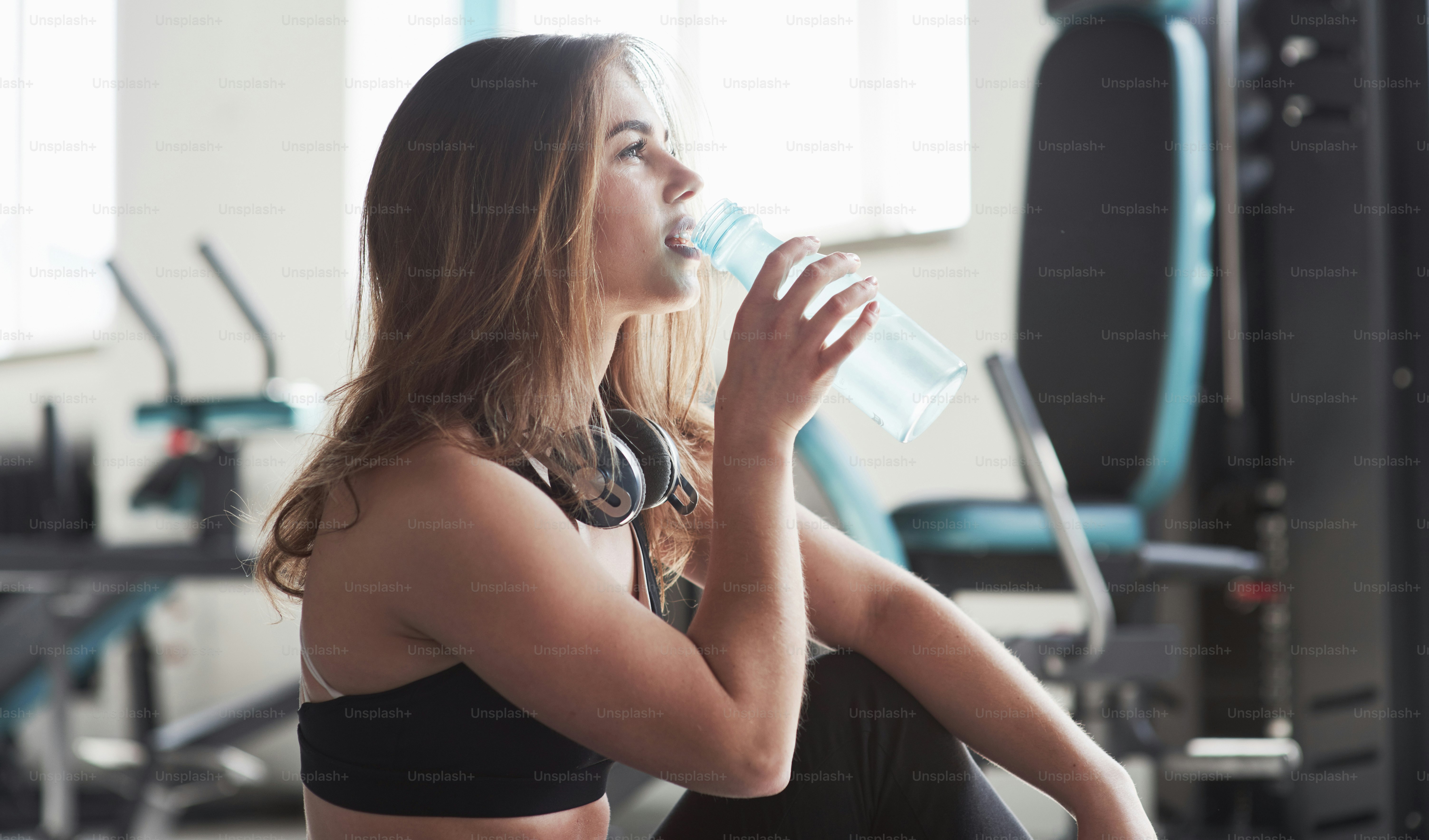 Time to drink water. Photo of gorgeous blonde woman in the gym at her weekend time.