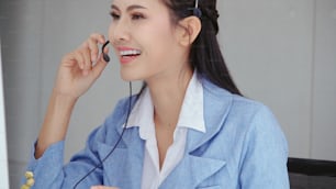 Customer support agent or call center with headset works on desktop computer while supporting the customer on phone call. Operator service business representative concept.