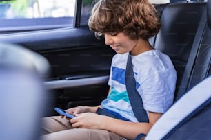 Little boy looking at screen of his gadget. Travelling by car concept