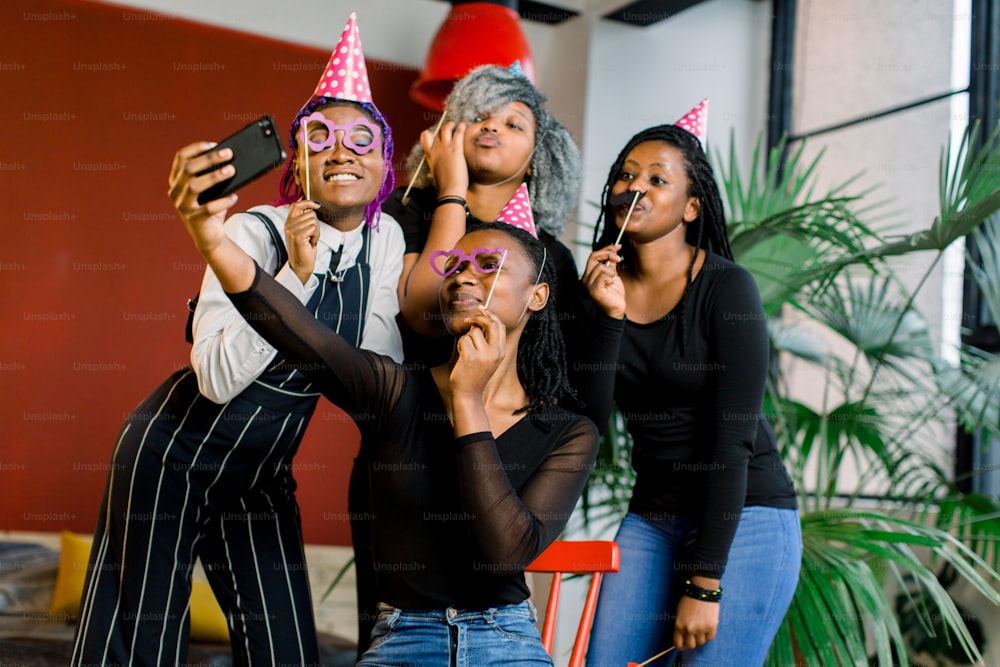 Afroamerikanische Mädchen feiern den Geburtstag ihrer Freundin, glücklich, lachen und machen Selfi