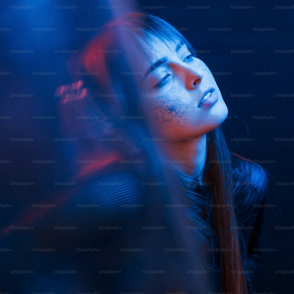 Sensualité et plaisir. Tourné en studio dans un studio sombre avec une lumière au néon. Portrait de jeune fille.