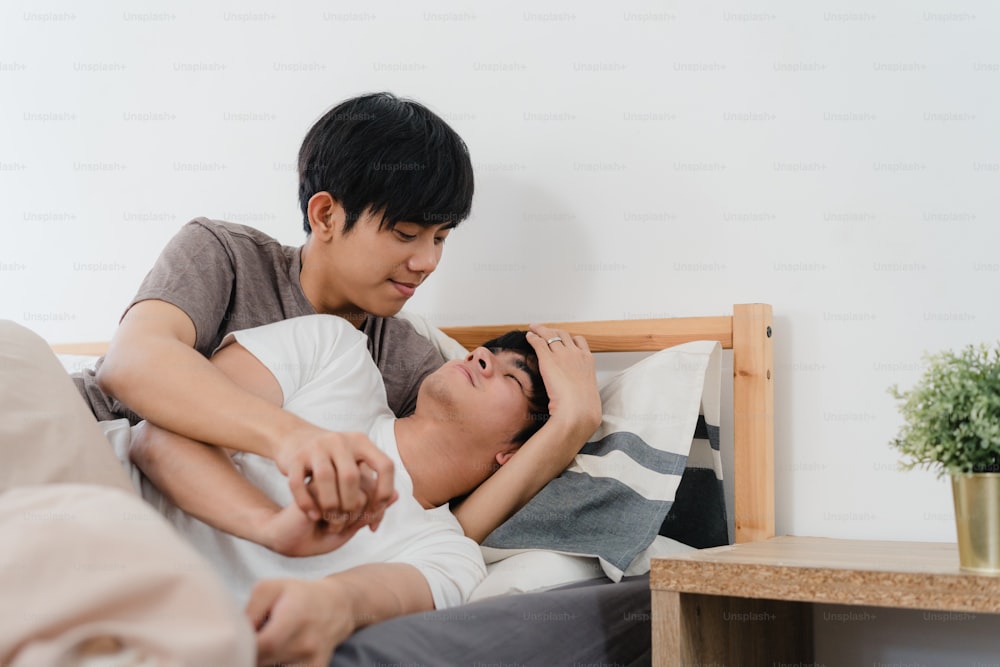 Asiatisches schwules Paar küsst und umarmt sich zu Hause im Bett. Junge asiatische LGBTQ-Männer entspannen sich glücklich zusammen und verbringen romantische Zeit nach dem Aufwachen im Schlafzimmer zu Hause im Morgenkonzept.
