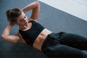 Bauchmuskeln auf dem Boden im Fitnessstudio machen. Schöne weibliche Fitnessfrau.