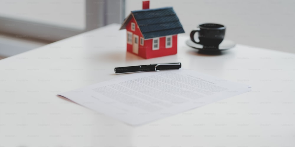 Foto cortada do documento do contrato de empréstimo imobiliário com modelo de casa pequena, conceito imobiliário