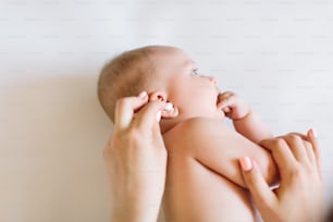 Mother hand cleaning baby ear on towel.