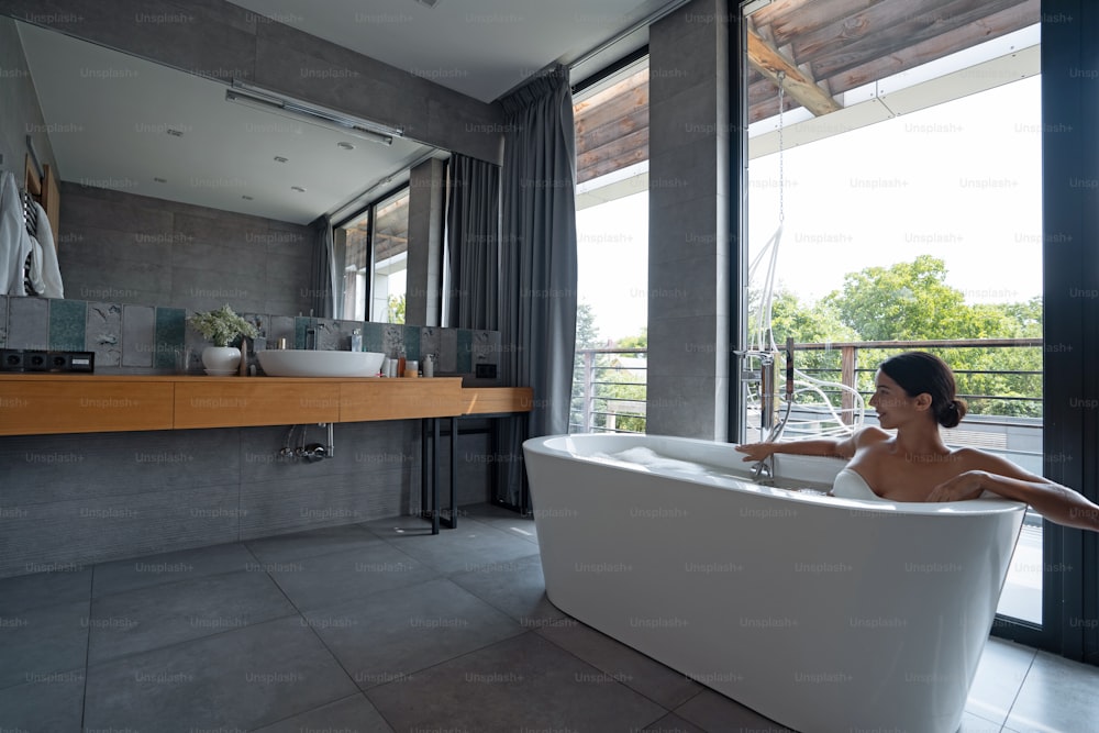 Attractive calm Caucasian young female enjoying a bubble bath