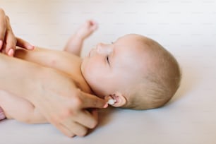 Mother hand cleaning baby ear on towel.