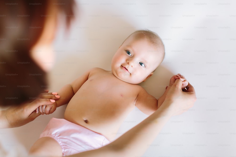 Baby massage. Mother massaging and doing gymnastic with arms of her kid.