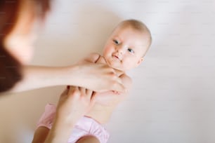 Baby massage. Mother massaging and doing gymnastic with arms of her kid.