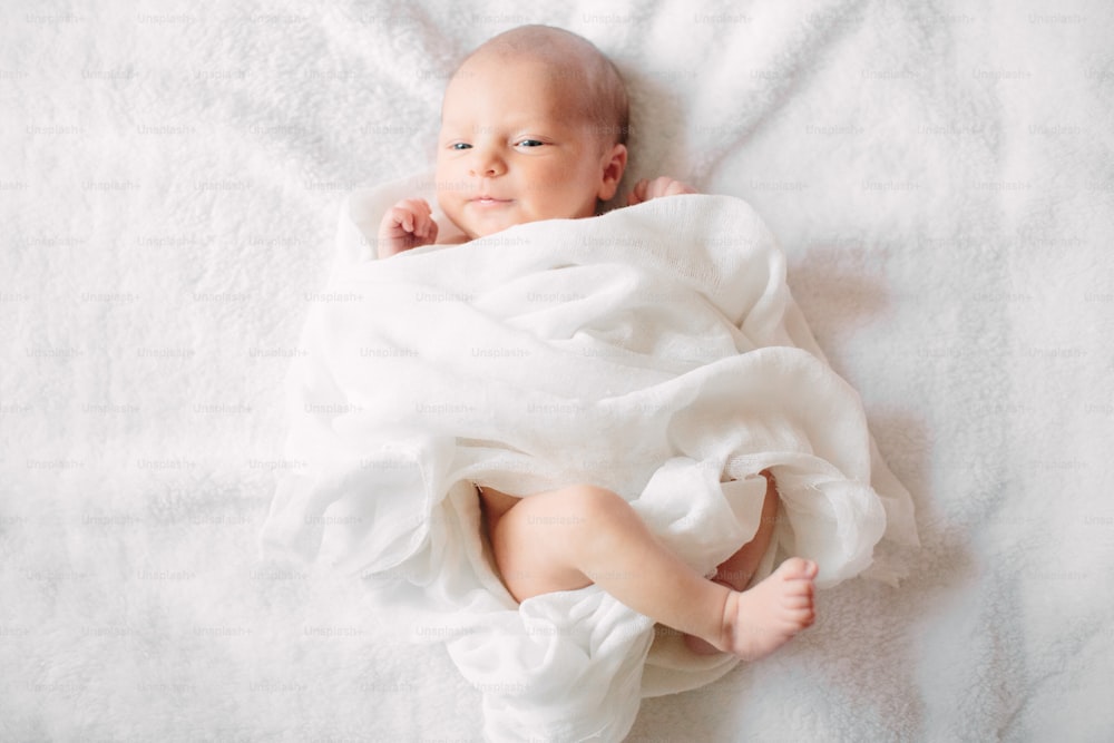 Süßes kleines neugeborenes Mädchen, das auf pelzigem Tuch schläft und weißes Stirnband trägt