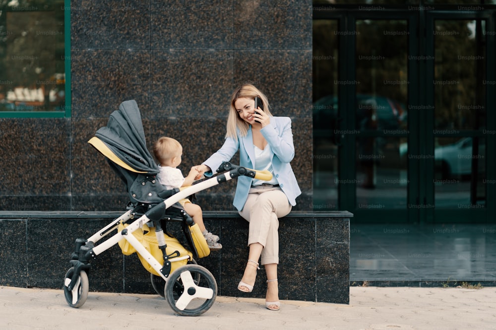 Portrait of a successful business woman in blue suit with baby. Business woman talking on the phone